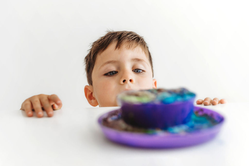 Boy peering over a table looking at a magical potion fizzing over the top of a bowl