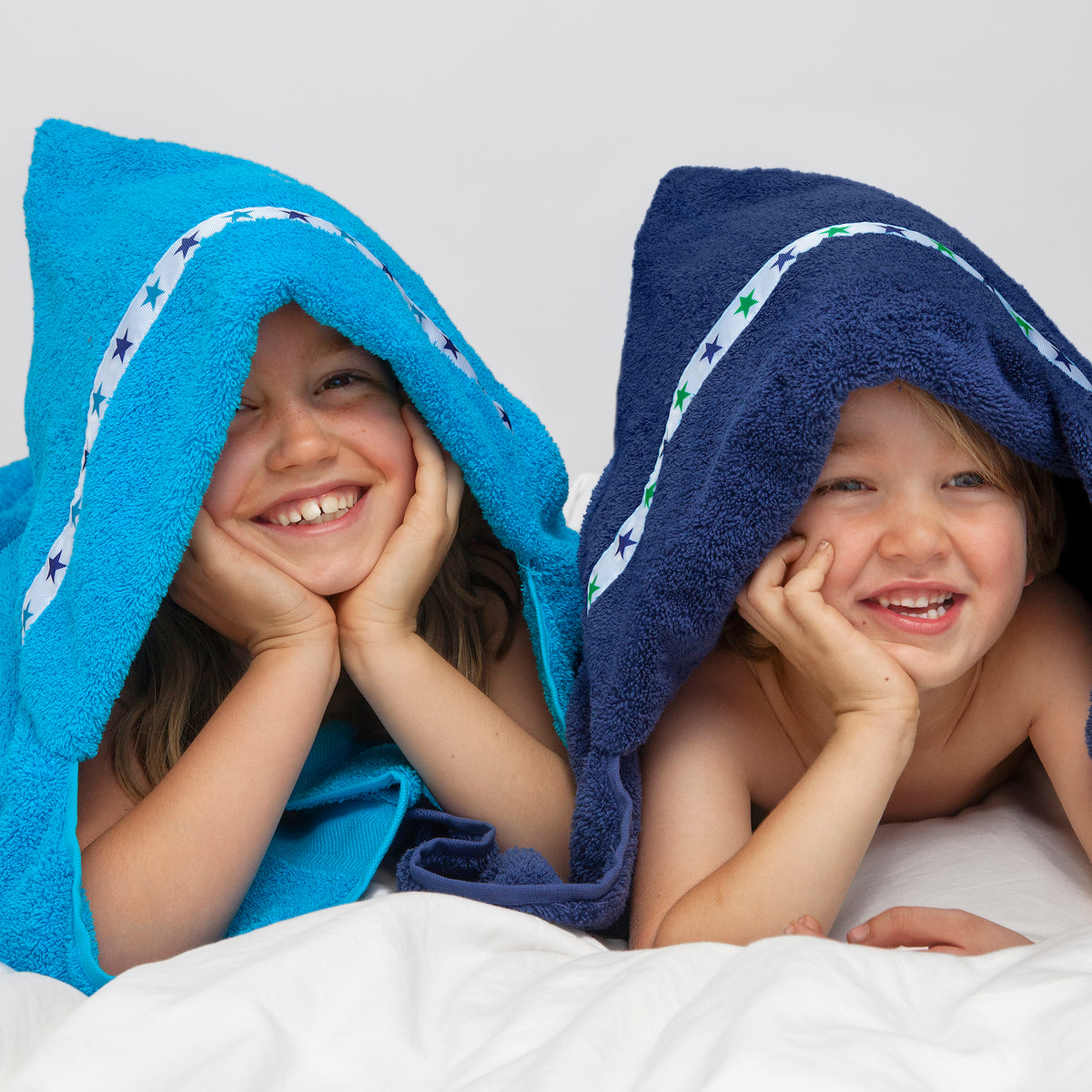 Two children wearing big hooded towels