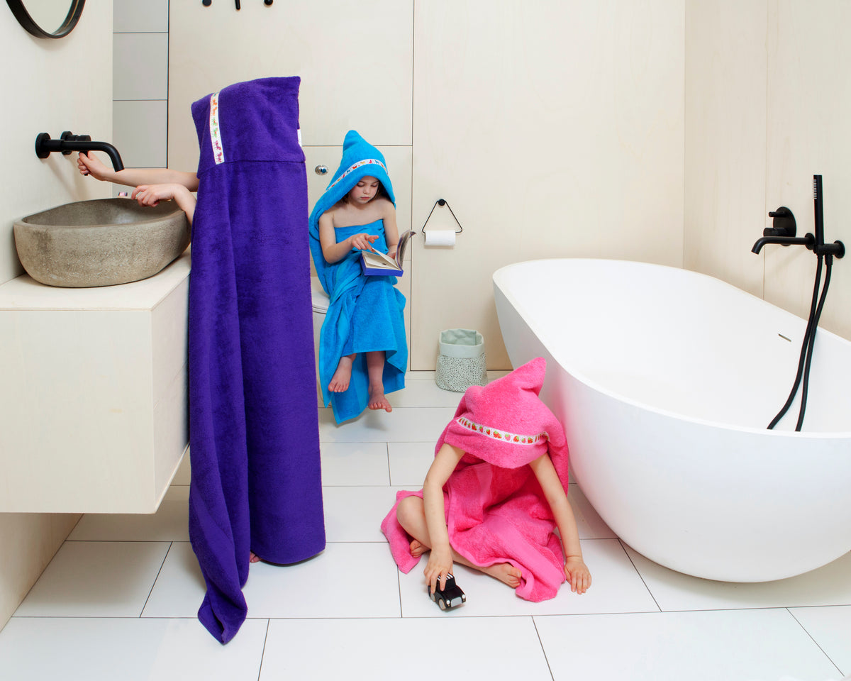 Children wearing hooded towels in a stylish bathroom