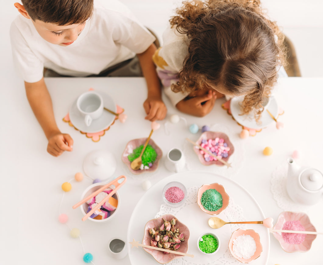 Overhead view of two children playing with colourful potion ingredients at a table