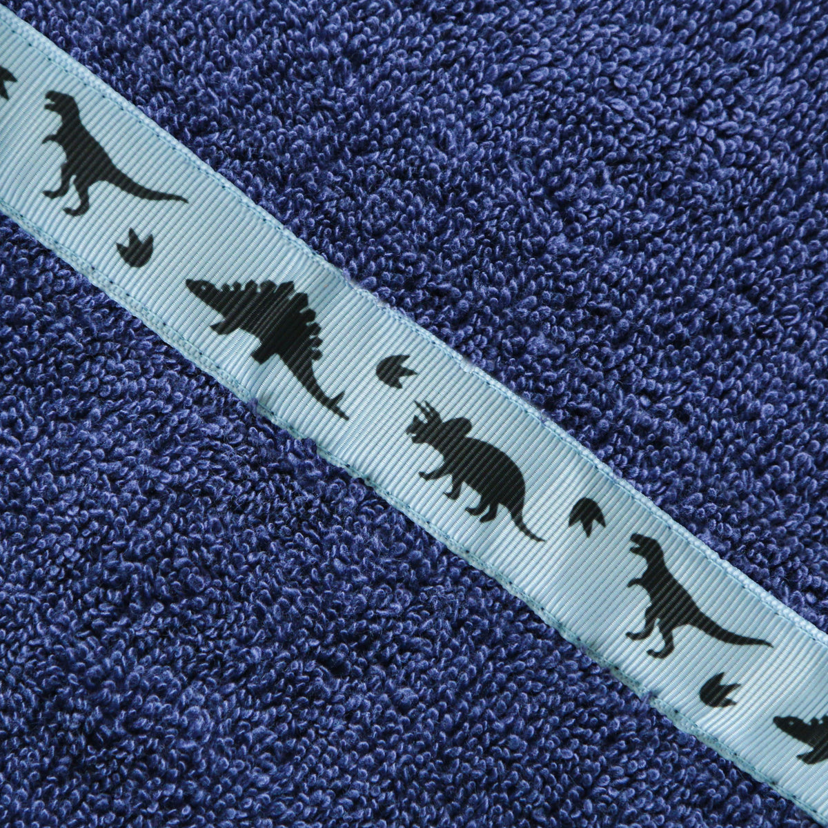 Close of of the Dinosaurs trim of a navy blue hooded towel