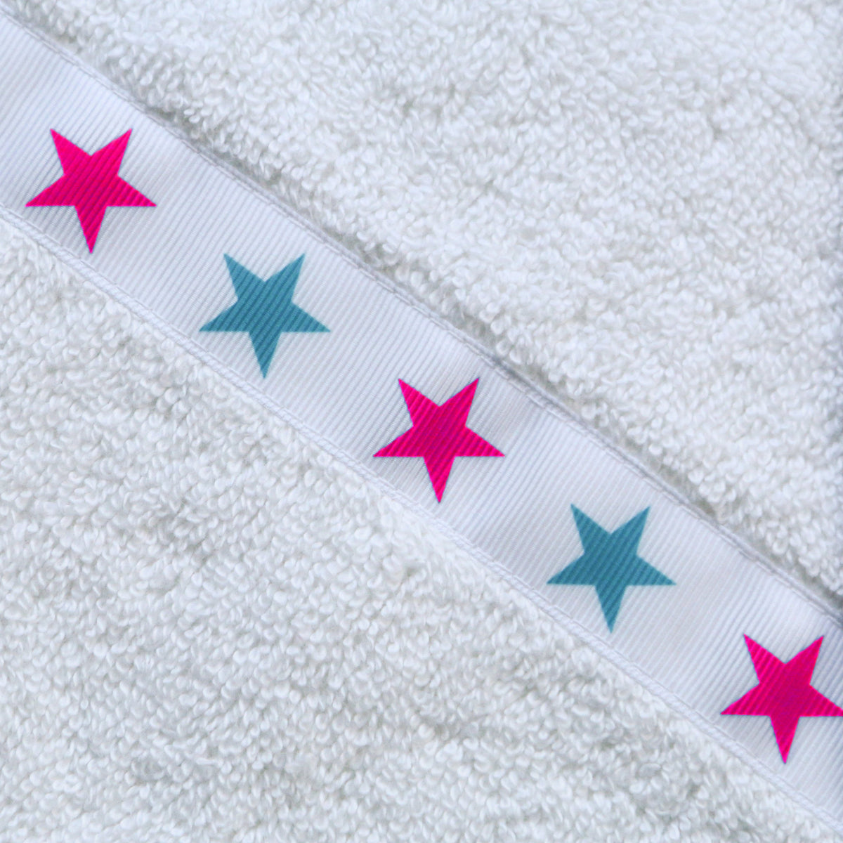 Close up of the Pink Aqua Stars trim of a white hooded towel 