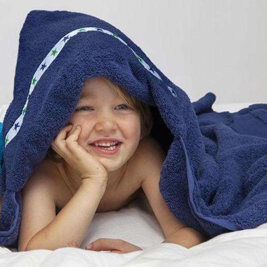 Boy laid on his tummy with a hooded towel draped over him