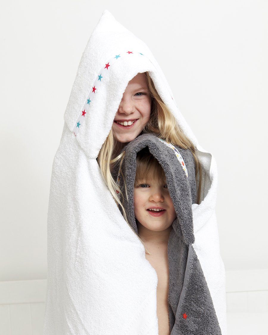 Brother and sister stood in hooded towels, the girl in a white towel with Pink and Aqua Stars trim; the boy in a grey hooded towel with Outer Space trim